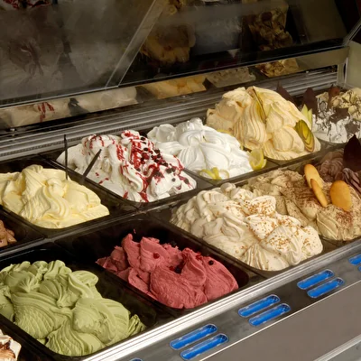 Banco gelateria con vaschette di gelato di gusti diversi in vetrina refrigerata