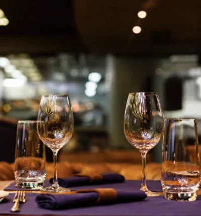Tavolo elegante apparecchiato con calici e tovaglioli viola in un ristorante della catena