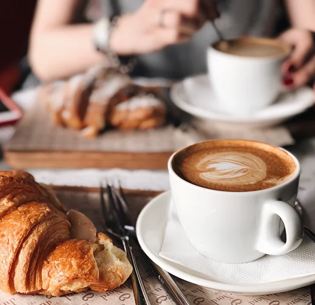 Tazza di cappuccino con latte art e cornetti su un tavolo da bar