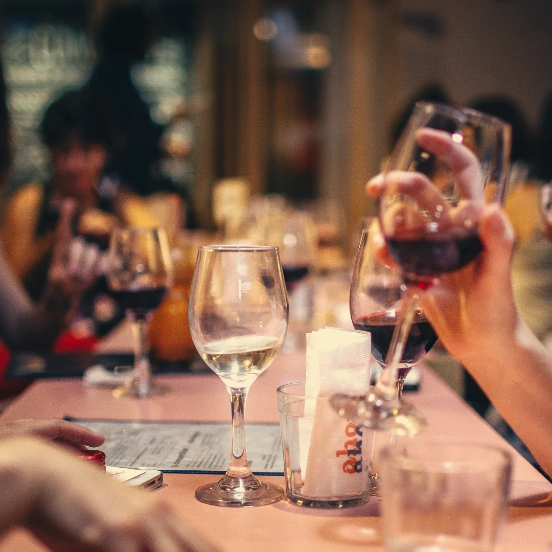 Calici di vino bianco e rosso sollevati in un brindisi al tavolo di un ristorante